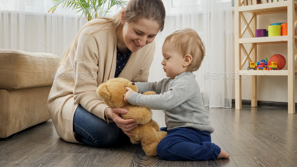 Cute baby boy with mother playing on floor with teddy bear - Stock Photo - Images