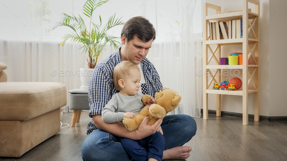 Young father playing with his baby son with teddy bear toy and teaching him - Stock Photo - Images