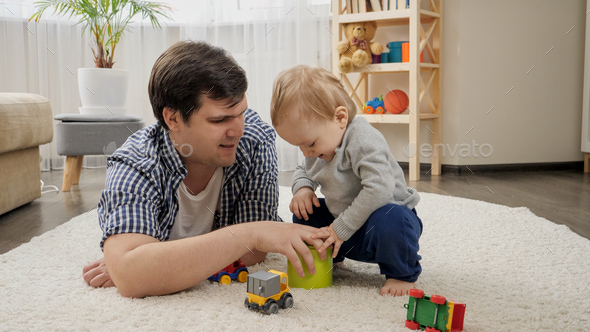 Little baby boy giving toys to his father for playing on carpet. - Stock Photo - Images