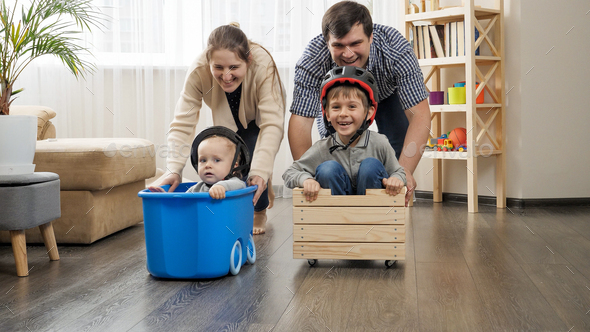 Happy family playing at home and having race in carts with children - Stock Photo - Images