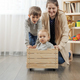 Cute baby boy sitting in wooden toy box while his family riding him at living room. - PhotoDune Item for Sale