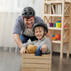 Funny shot of young father playing with his son and having race in wooden cart at home. - PhotoDune Item for Sale