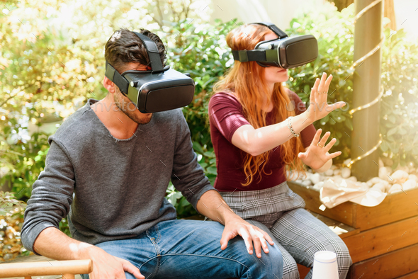 Couple trying virtual reality visors on terrace