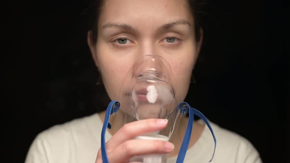 Young woman puts an inhaler mask on her face and treats the lungs alt