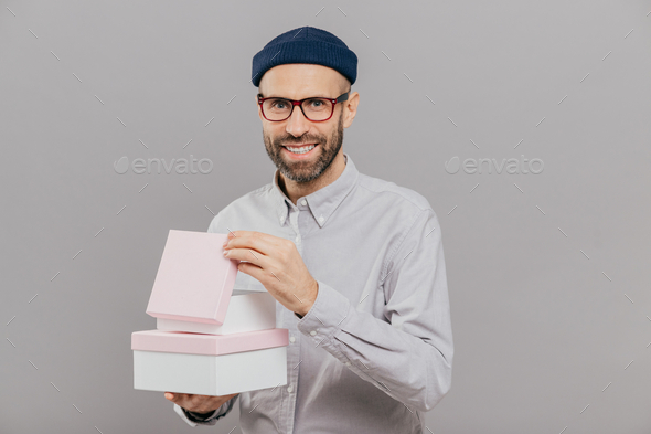 Man has stubble, carries boxes with present, opens one of them, has ...