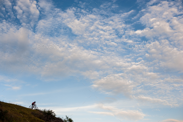 Silhouette of a cross country cyclist going downhill - Stock Photo - Images