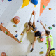 Rock climbers in climbing gym. Young woman climbing bouldering problem, man giving her instructions. - PhotoDune Item for Sale