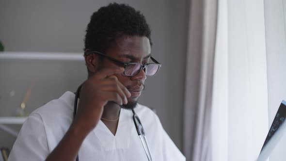 Male African American Neurologist Analyzing Xray Sighing Taking Off Eyeglasses alt