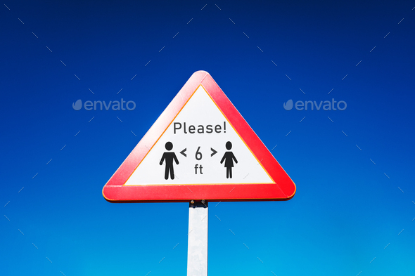 Triangular traffic sign to indicate social distancing and stay alert.