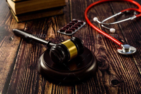 Medical malpractice and errors makes doctors and patients go to court, gavel on legal books.