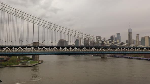 An aerial view over the East River on a cloudy day. The drone camera trucks right along the north si alt