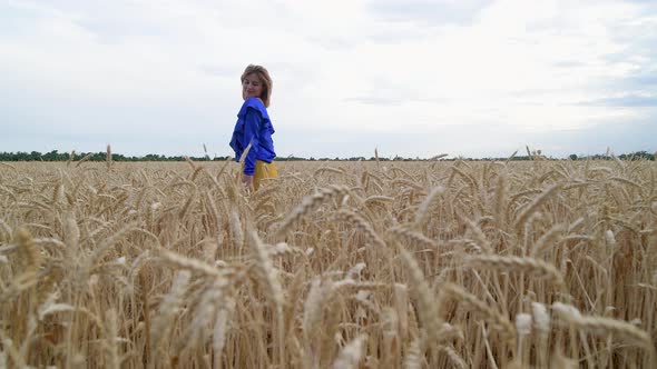 Beautiful Ukrainian Woman Wearing Dress in Ukrainian National Flag Colours Blue and Yellow at Wheat alt