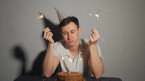 Sad Lonely Man in Party Hat Celebrating Birthday Alone and Holding the Sparkler alt