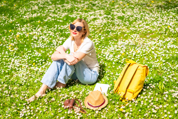 Young blonde girl in a hat unwinding and breathing pure haire in the spring  in a park in the city