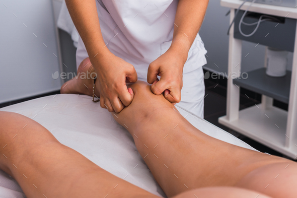 Therapist giving a calf massage to a woman with knuckles in spa center