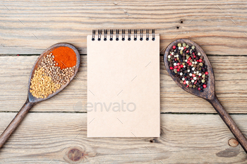 Food background with spices in spoons and open blank notebook with copy space