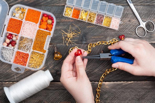 Woman making handmade jewellery. Handmade accessories. Box with beads, glass hearts, accessories