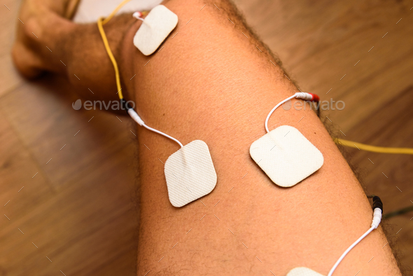 An injured athlete applies ems electrodes to his legs to recover muscle tone