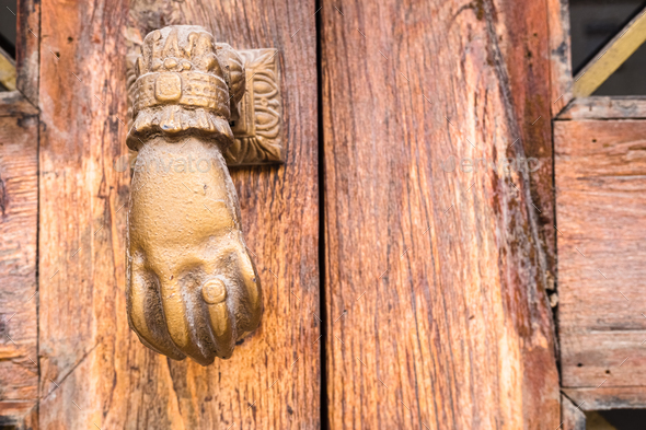 Old hand-shaped knob to knock on an old wooden door.