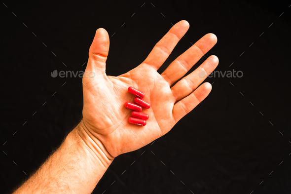 Man\'s hand holding a handful of medicine pills, to treat addictive diseases