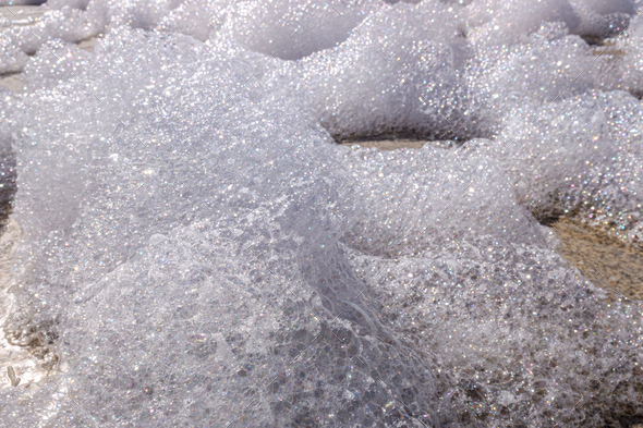 Close-up detail of the white foam of a cleaning soap on the floor.