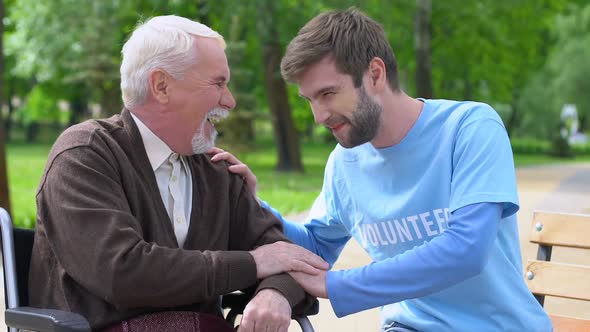 Male Volunteer and Elderly Disabled Man Laughing in Park, Lonely Pensioners Care alt