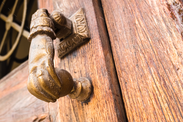 Old hand-shaped knob to knock on an old wooden door.