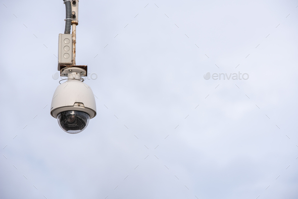 Security camera hung to monitor people in a city, isolated over blue sky and clear background