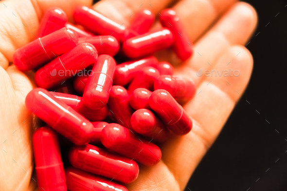 Man\'s hand holding a handful of medicine pills, to treat addictive diseases