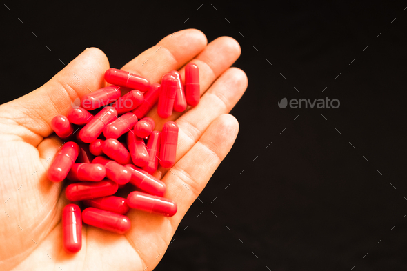 Man's hand holding a handful of medicine pills, to treat addictive diseases