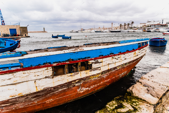 Bari, Italy - March 12, 2019: Blue wooden boat washed by time and waves in a harbor.