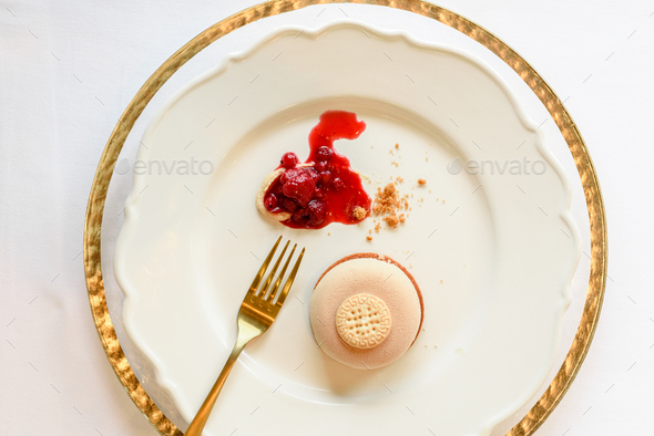Ice cream dessert elegantly presented with strawberry jam in luxury dishes and golden linens.