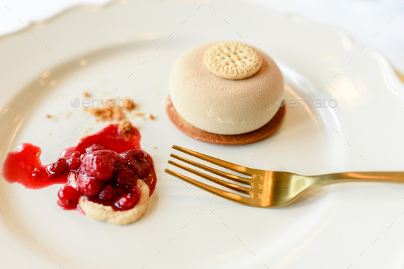 Ice cream dessert elegantly presented with strawberry jam in luxury dishes and golden linens.