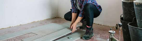 Female bricklayer placing tiles to install a floor