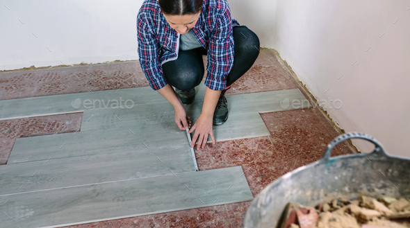 Female bricklayer measuring tiles to install a floor
