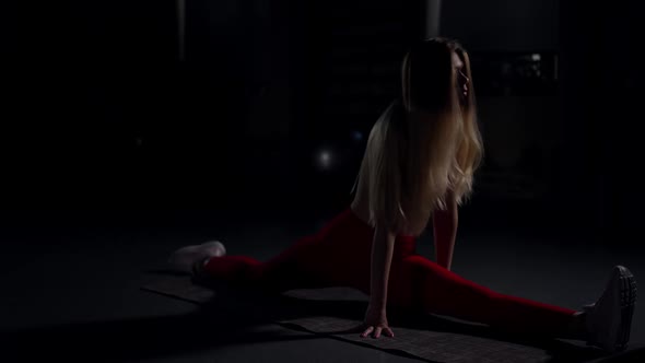 Wide Shot Slim Woman in Red Leggins Sitting in Split Raising Hands in Slow Motion alt