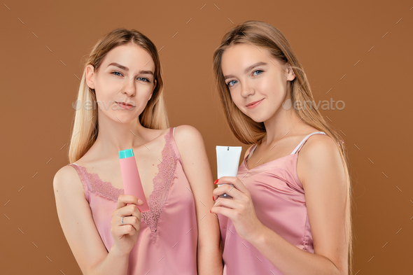 Two young girls holding acne cream in hands