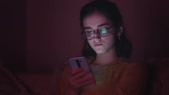 Sad Alone Teen Girl Sits in the Evening Near Tv and Uses the Phone Bad Mood Jealousy Cinematic Shot