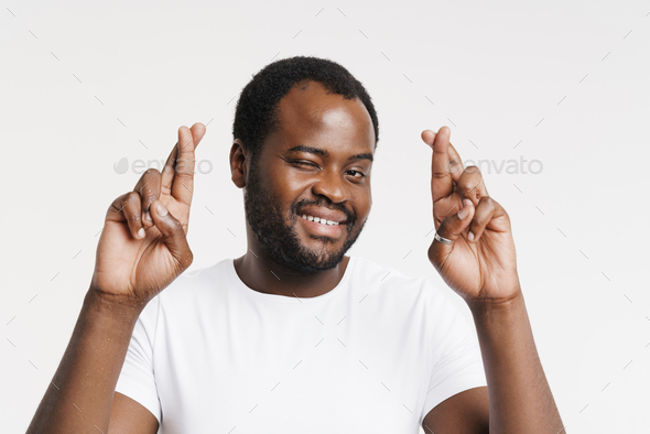 Black bristle man smiling while holding fingers crossed for good luck - Stock Photo - Images
