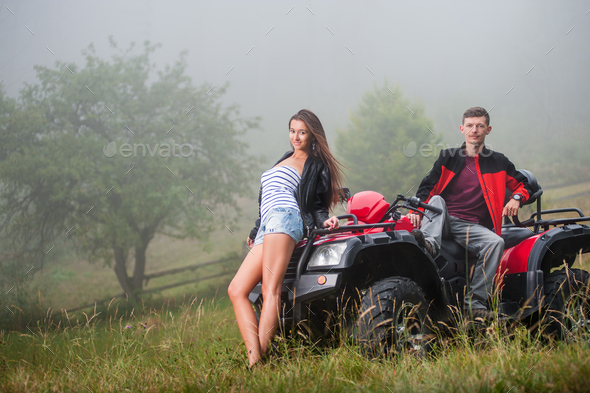 Happy couple near four-wheeler ATV in foggy nature