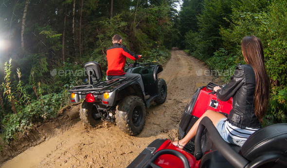 Couple driving four-wheelers ATV offroad
