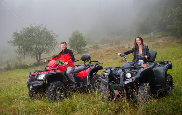 Happy couple driving four-wheeler ATV offroad