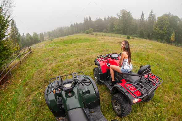 Pretty lady driving four-wheelers ATV in foggy nature
