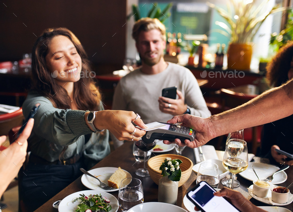 Woman paying with card in restaurant - Stock Photo - Images
