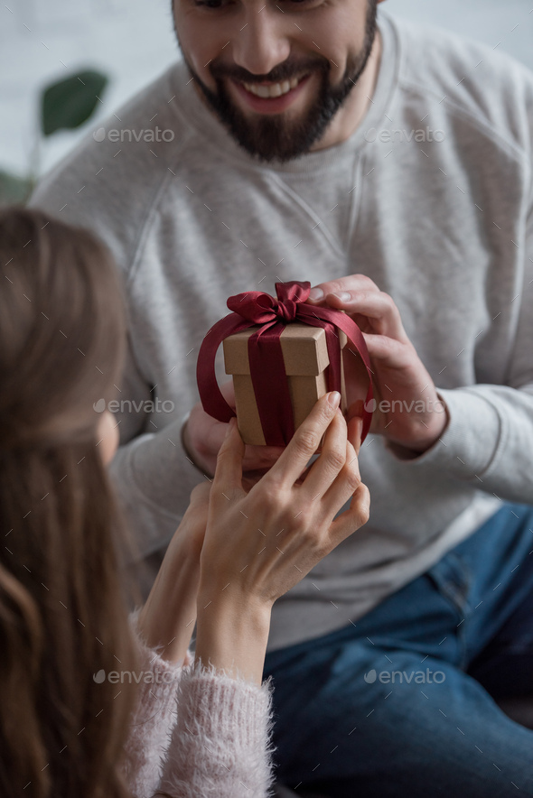 cropped image of boyfriend presenting gift to girlfriend on 8 march at home