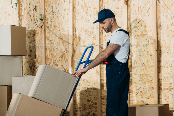 Loader man adjusting cardboard boxes on delivery cart