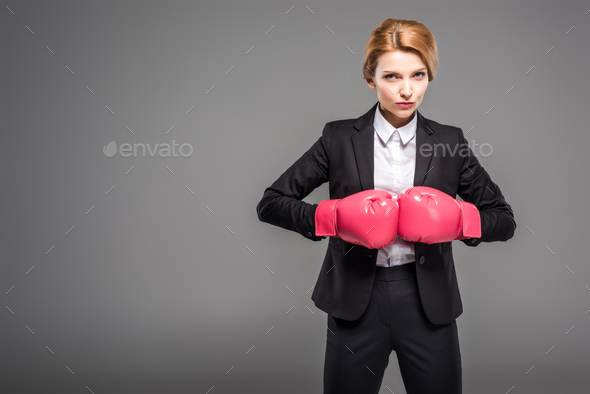 businesswoman in suit and formal wear and pink boxing gloves, isolated on grey