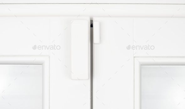 Wireless alarm sensor for window and door on white wooden sash - Stock Photo - Images