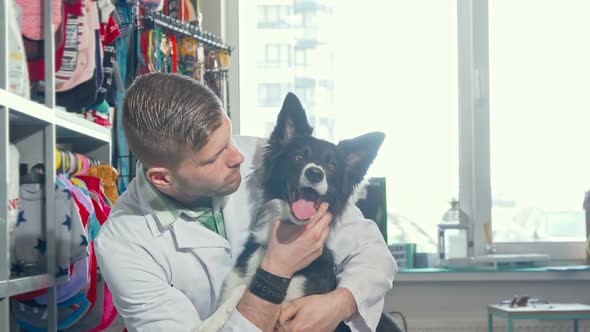 Handsome Cheerful Male Veterinarian Smiling To the Camera Hugging Adorable Dog alt