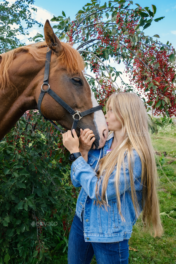 A young blonde woman kisses her horse. love positive emotions in human and animal communication.